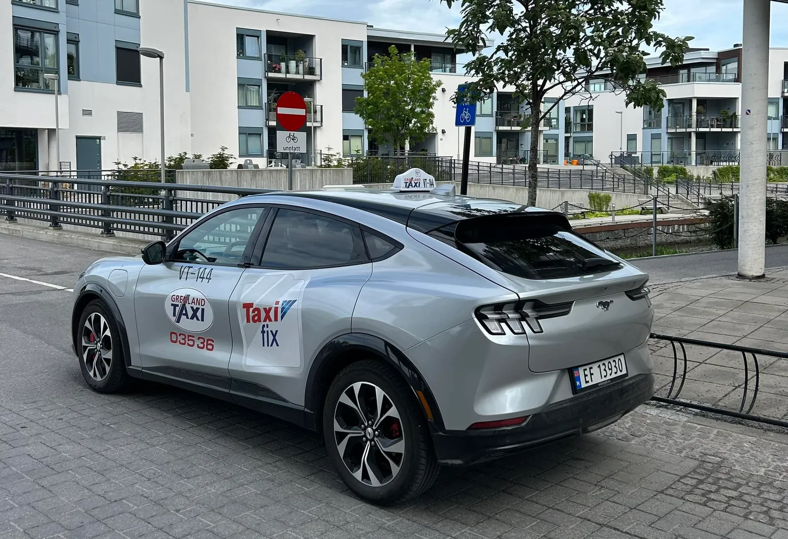 Lyst sølvfarget elbil fra Grenland Taxi med Grenland Taxi-logo, 03536 og Taxifix-logo på bakdøra